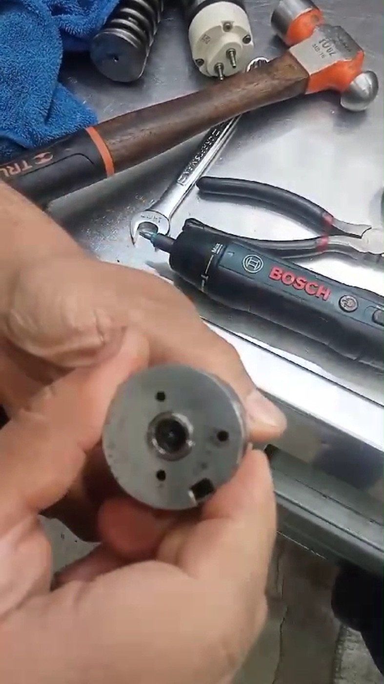 Manos trabajando una pieza de inyector
